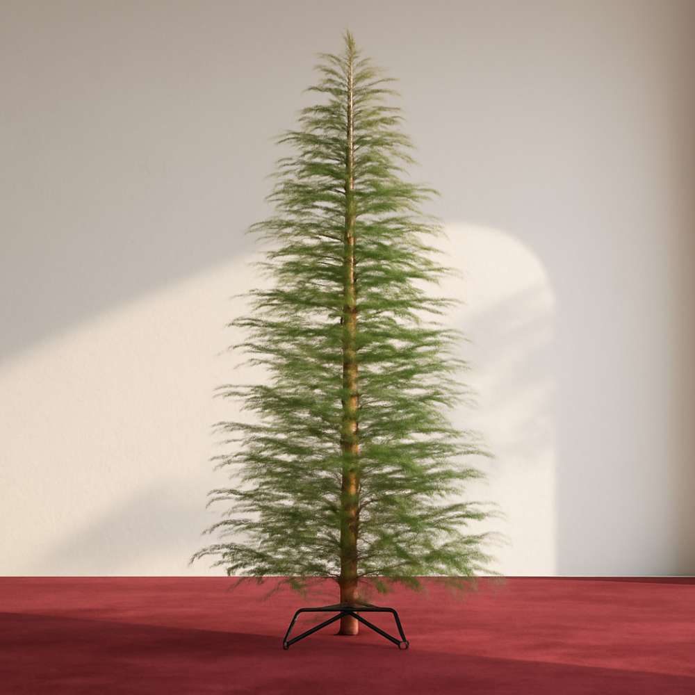 A slim artificial Christmas tree on a red carpet, ideal for small spaces.