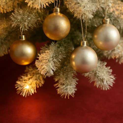 Close-up of golden Christmas ornaments on a snowy tree branch, adding a festive touch.