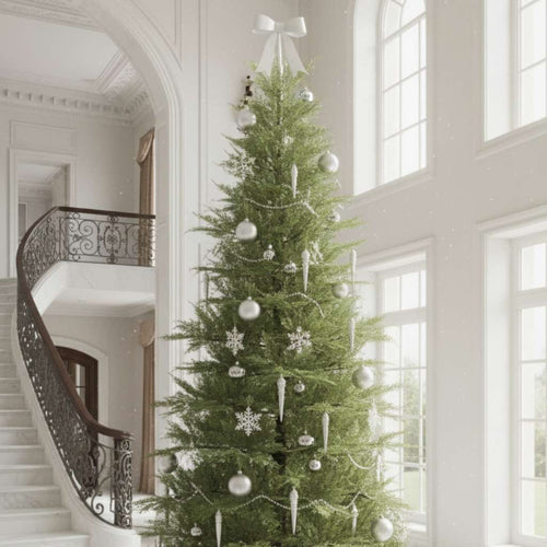 An elegant premium Christmas tree with white and silver decor in a bright, grand entryway.
