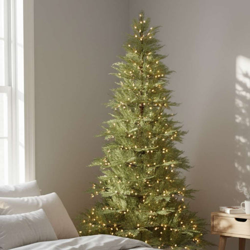 A minimalist artificial Christmas tree bringing a festive touch to the corner of a calm, sunlit bedroom.