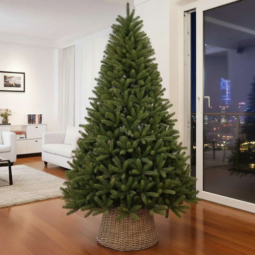 A full, unlit premium artificial Christmas tree with a wicker collar in a modern city apartment.