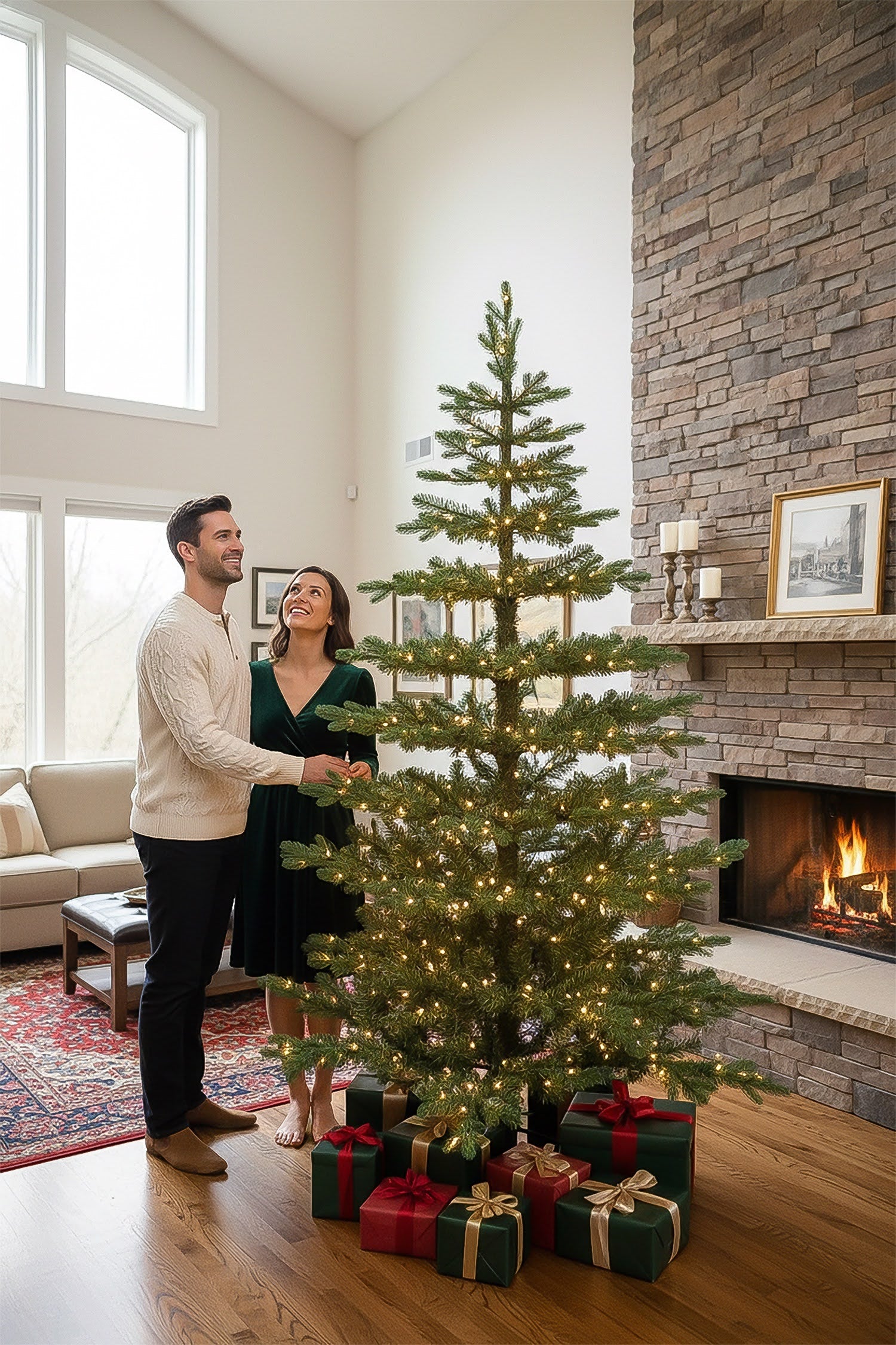A couple admiring their tall 9-foot pre-lit skinny Christmas tree next to a cozy stone fireplace.
