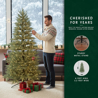 Man decorating a 6-foot space saving Christmas tree in a modern living room next to a window with a snowy view.